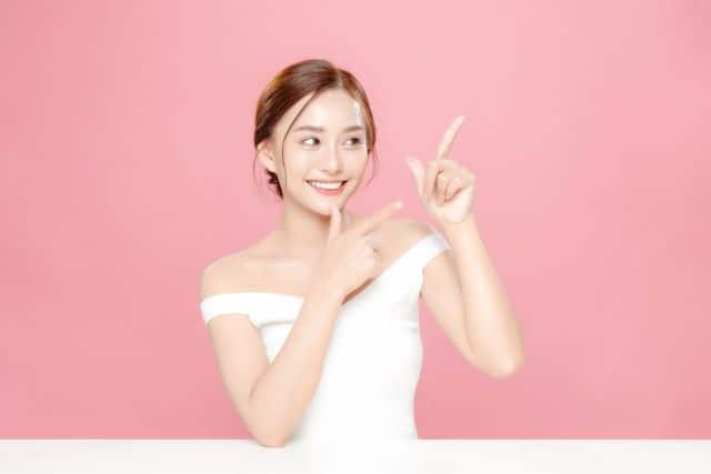 横を指さす女性